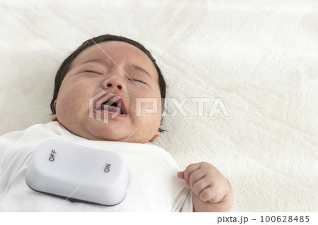 泣く赤ちゃんと玩具のスイッチ(生後3か月、男の子、日本人)。背中スイッチのイメージ 泣く赤ちゃんと玩具のスイッチ(生後3か月、男の子、日本人)。背中スイッチのイメージ 100628485