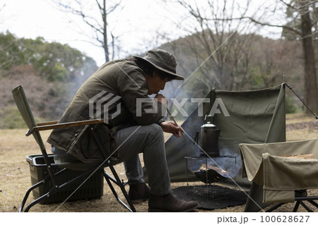 ソロキャンプで焚き火をする男性 ソロキャンプで焚き火をする男性 100628627