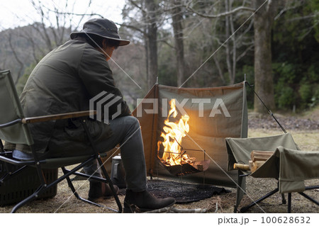 ソロキャンプで焚き火をする男性 100628632
