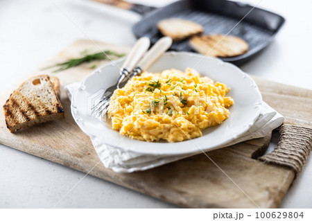 Plate of scrambled organic eggs served with bread toasted on a griddle pan 100629804