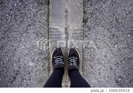 Woman's feet on the asphalt 100630428