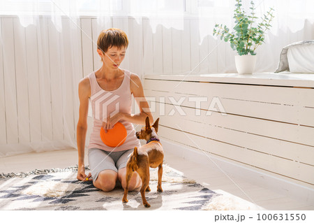 Cute woman practicing yoga with dog breed pygmy pinscher, enjoy and relax 100631550