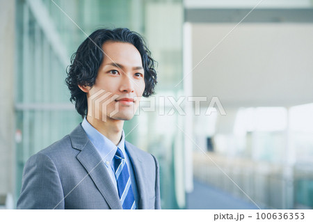 オフィスの廊下で腕組みをする若いビジネスマンの男性 100636353