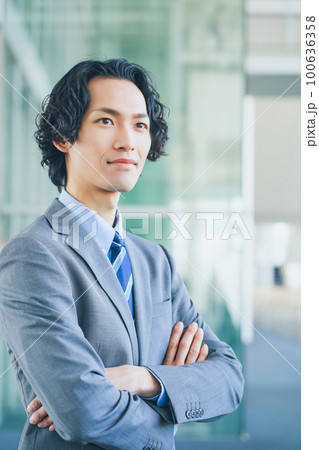 オフィスの廊下で腕組みをする若いビジネスマンの男性 100636358