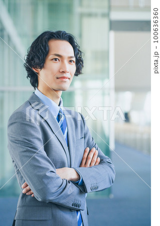 オフィスの廊下で腕組みをする若いビジネスマンの男性 100636360