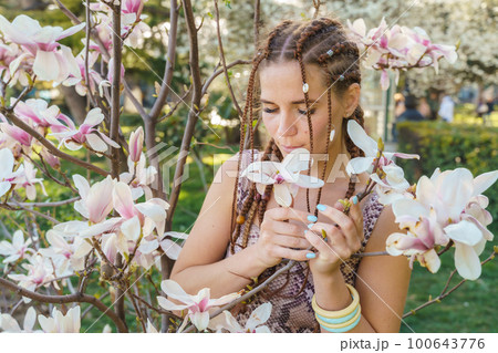 Magnolia flowers, a girl smells a blooming magnolia in the park in the sun, enjoys her vacation. Magnolia flowers, a girl smells a blooming magnolia in the park in the sun, enjoys her vacation. 100643776