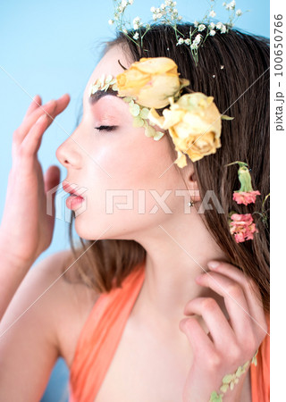 Cosmetics and manicure. Close-up portrait of attractive woman with dry flowers on her face and hair, pastel color, perfect make-up and skin on blue background. Fresh, trendy, spring retouched portrait Cosmetics and manicure. Close-up portrait of attractive woman with dry flowers on her face and hair, pastel color, perfect make-up and skin on blue background. Fresh, trendy, spring retouched portrait 100650766