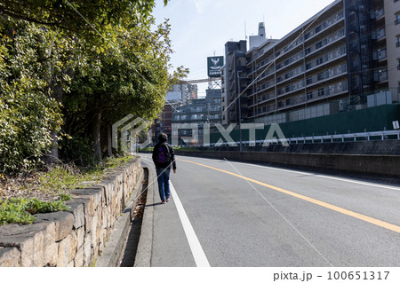 車道の端の路側帯を歩く男性 100651317