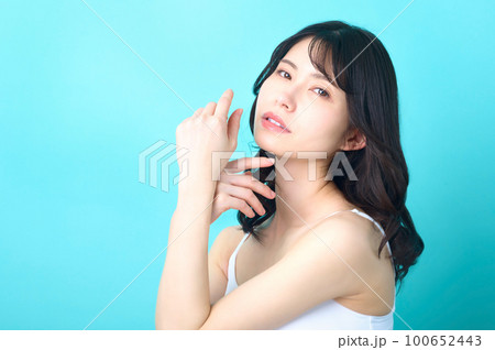 ブルーの背景の前でポーズするノースリーブの女性の美容イメージ ブルーの背景の前でポーズするノースリーブの女性の美容イメージ 100652443