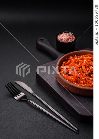 Dried squid chopped into slices and seasoned with sesame seeds and spices Dried squid chopped into slices and seasoned with sesame seeds and spices 100659789