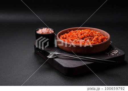 Dried squid chopped into slices and seasoned with sesame seeds and spices 100659792