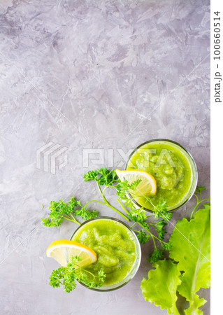 Refreshing smoothies from cucumber, green apple, fresh herbs and lemon juice in transparent glasses on the table. The concept of a healthy diet. Vegetarian menu. Top view 100660514