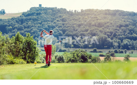 Golf player hitting ball long with driver 100660669