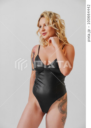a sexy blonde with tattoos in a leather swimsuit 100664442