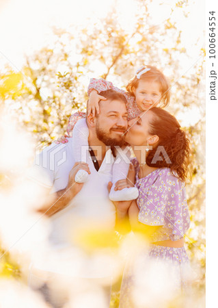 in the sun's rays. happy family in a blooming spring garden.  100664554