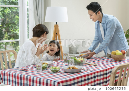 ファミリー　食卓　イメージ　テーブルに料理を運ぶ父親 100665256