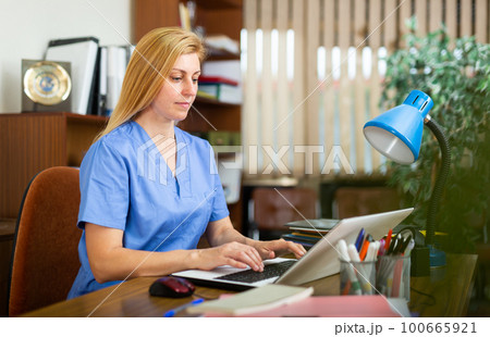 Woman doctor sitting at workplace with computer in office 100665921