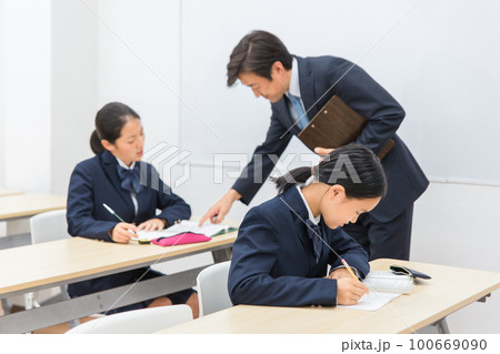 塾・学校の教室で先生に勉強を教わる小学生・中学生・高校生の子供（冬季講習・予備校） 100669090