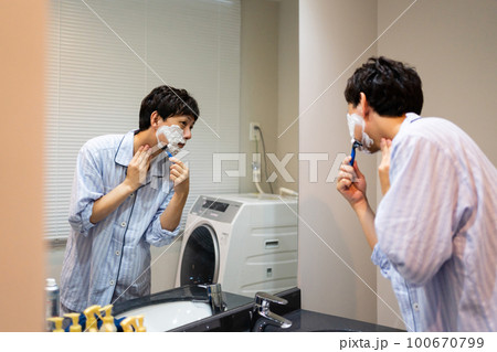 T字カミソリでヒゲ剃りをする40代男性 100670799