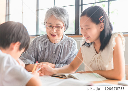 家のダイニングで孫の夏休みの宿題を教える高齢者女性と小学生の子供(帰省・里帰り) 家のダイニングで孫の夏休みの宿題を教える高齢者女性と小学生の子供(帰省・里帰り) 100676783