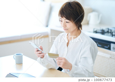 カードを持ってスマートフォンを操作する女性 100677473