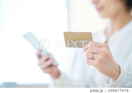 カードを持ってスマートフォンを操作する女性 100677476