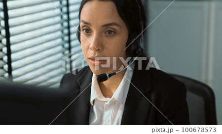 Competent female operator working on computer and while talking with clients. 100678573