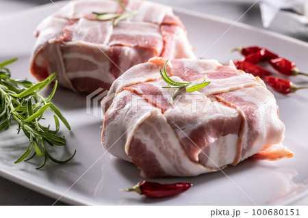 Neatly wrapped packages of food in bacon to be cooked with rosemary herb and fresh chilli Neatly wrapped packages of food in bacon to be cooked with rosemary herb and fresh chilli 100680151