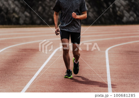 陸上競技のトラックの直線を走る男性ランナー 100681285