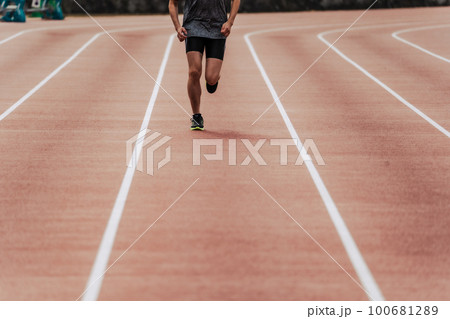 陸上競技のトラックの直線を走る男性ランナー 100681289