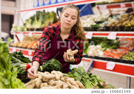 Young saleswoman puts ginger roots on the counter Young saleswoman puts ginger roots on the counter 100681349