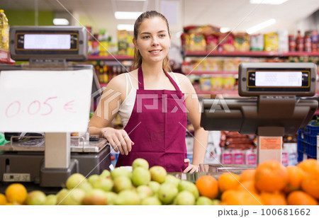 Portrait of a smiling seller girl standing behind the counter with scales Portrait of a smiling seller girl standing behind the counter with scales 100681662