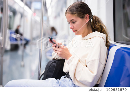 Portrait of woman holding smart phone in a subway train 100681670