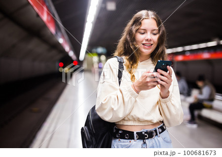 Positive girl in the subway, texting on a mobile phone with friends 100681673