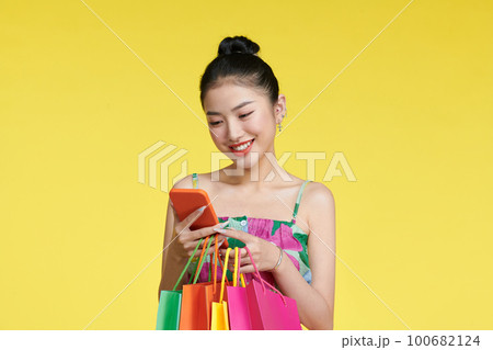 young woman holding shopping bags and smart phone 100682124