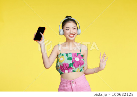 Young woman dancing while listening music with headphones and cellphone 100682128