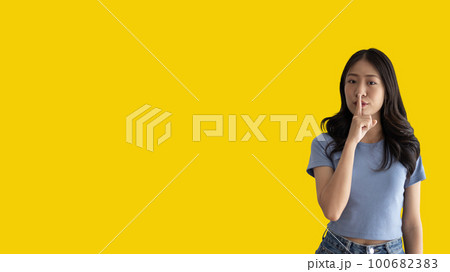 Asian woman doing silent gesture with finger, Noiseless symbol, Noisy mall, Hide a secret, Do not speak. shut your mouth, Noiseless signal transmission, Isolated on yellow background. Asian woman doing silent gesture with finger, Noiseless symbol, Noisy mall, Hide a secret, Do not speak. shut your mouth, Noiseless signal transmission, Isolated on yellow background. 100682383