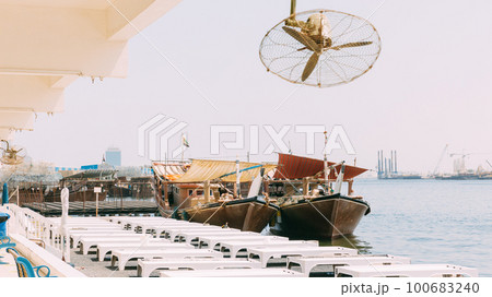 Many Dhow, sailboat, sailing vessel boat is moored to the city pier, jetty in sunny summer day. Urban city background. Port in Dubai, United Arab Emirates, UAE Many Dhow, sailboat, sailing vessel boat is moored to the city pier, jetty in sunny summer day. Urban city background. Port in Dubai, United Arab Emirates, UAE 100683240