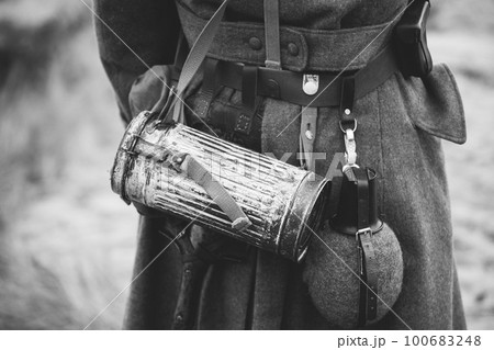 Re-enactor Dressed As German Wehrmacht Infantry Soldier In World War Ii On Marsch. View From Back. German Military Dress Of A German Soldier At World War II. Black And White Colors 100683248