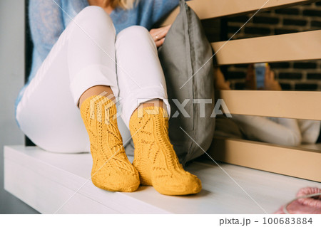 Comforting cozy woman in knitted woolen winter yellow socks, whi Comforting cozy woman in knitted woolen winter yellow socks, whi 100683884
