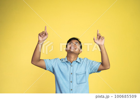 Asian man looks up with finger pointing upwards on isolated 100685509
