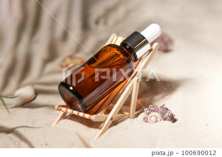 Summer sunscreen essence in deck chair on the sand backgroundwith shells ans seastar. B 100690012