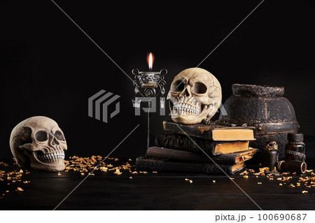 Realistic model of a human skull with teeth on a wooden dark table, black background. Medical science or Halloween horror concept. Close-up shot. Realistic model of a human skull with teeth on a wooden dark table, black background. Medical science or Halloween horror concept. Close-up shot. 100690687