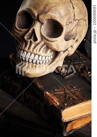 Realistic model of a human skull with teeth on a wooden dark table, black background. Medical science or Halloween horror concept. Close-up shot. Realistic model of a human skull with teeth on a wooden dark table, black background. Medical science or Halloween horror concept. Close-up shot. 100690695