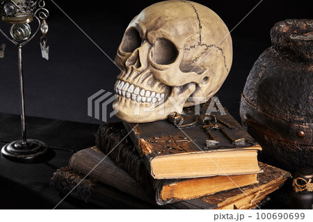 Realistic model of a human skull with teeth on a wooden dark table, black background. Medical science or Halloween horror concept. Close-up shot. Realistic model of a human skull with teeth on a wooden dark table, black background. Medical science or Halloween horror concept. Close-up shot. 100690699