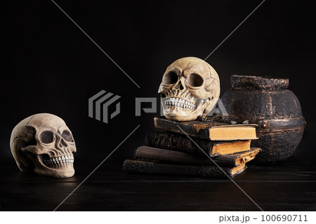 Realistic model of a human skull with teeth on a wooden dark table, black background. Medical science or Halloween horror concept. Close-up shot. Realistic model of a human skull with teeth on a wooden dark table, black background. Medical science or Halloween horror concept. Close-up shot. 100690711