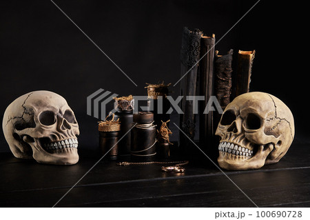 Realistic model of a human skull with teeth on a wooden dark table, black background. Medical science or Halloween horror concept. Close-up shot. Realistic model of a human skull with teeth on a wooden dark table, black background. Medical science or Halloween horror concept. Close-up shot. 100690728
