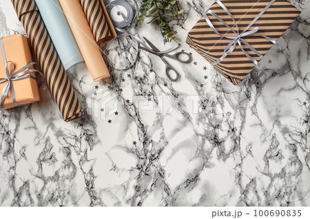 Different sizes, striped and plain, brown and pink paper gift boxes tied with silver ribbons on a marble background. Close-up, copy space, top view. 100690835