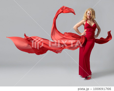 Attractive mature woman in a red evening dress with flying red fabric. Attractive mature woman in a red evening dress with flying red fabric. 100691766