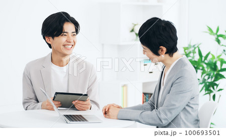 オフィスで会話するビジネスパーソン 100693501